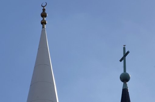Friedliches  Miteinander der Religionen: Die Spitze eines Minaretts (links) mit dem Halbmond und das Kreuz auf der Kirchturmspitze (rechts) – hier  in Mannheim. Foto: dpa