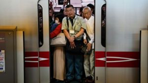 Menschen stehen dicht gedrängt in einem Pendlerzug, als sich die Zugtüren am Bahnhof Shinjuku in Tokio schließen. In japanischen U-Bahnen herrscht qualvolle Enge. Foto: Jae C. Hong/AP/dpa
