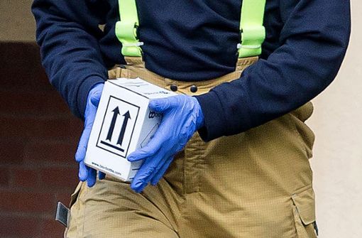 Ein Mitarbeiter der Feuerwehr trägt einen Karton mit Proben aus einem Mehrfamilienhaus in Hannover. Foto: dpa