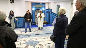 Betül Sahin, Beba Hadis und der Imam (von links) zeigen den  Besuchern den mit Teppichen ausgelegten Gebetsraum. Foto: Eva Herschmann