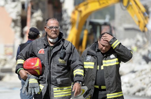 Rettungskräfte gehen am 25. August 2016 in der italienischen Stadt Amatrice an Trümmern vorbei. Foto: dpa