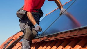 Ein Handwerker schraubt eine Photovoltaikanlage auf einem Dach fest. (Symbolbild) Foto: IMAGO/U. J. Alexander