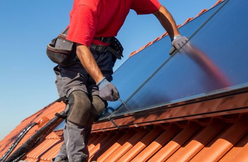Ein Handwerker schraubt eine Photovoltaikanlage auf einem Dach fest. (Symbolbild) Foto: IMAGO/U. J. Alexander