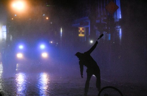 Ein Demonstrant wirft in der Nacht auf Sonntag in Hamburg im Schanzenviertel einen Flasche gegen einen Wasserwerfer. Foto: dpa