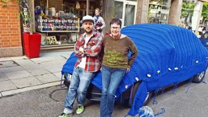 Manfred Schmidt lehnt mit  der „Strick-Oma“ Lucie Steier am bemützten VW-Beetle. Foto: Kathrin Wesely