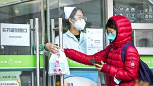 Eine Frau holt in einer Apotheke in Peking Covid-19-Antigen-Kits ab. Foto: dpa/Andy Wong