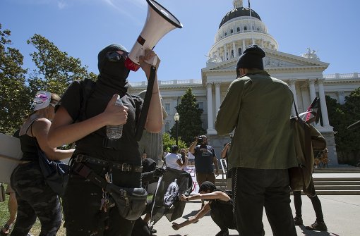 Bei der Kundgebung nationalistischer Gruppen in Sacramento tauchten 400 Gegendemonstrationen auf. Mitglieder der Antifa versuchen eine Flagge anzuzünden. Foto: AP