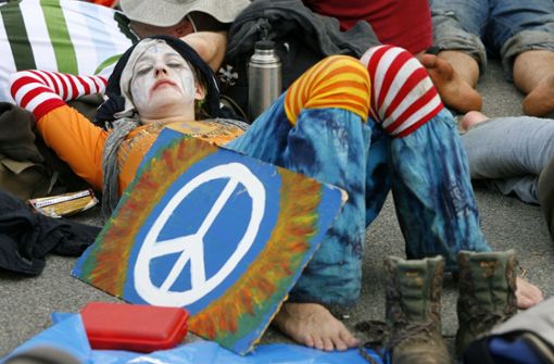 Eine Frau liegt mit einem selbst gemalten Peace-Zeichen auf dem Boden. Überall auf der Welt kennt man das Symbol. Foto: dpa