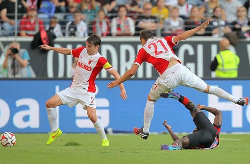 Der Frankfurter Constant Djakpa liegt am Boden während die Augsburger Dominik Kohr (rechts) und Paul Verhaegh versuchen an den Ball zu kommen. Foto: dpa