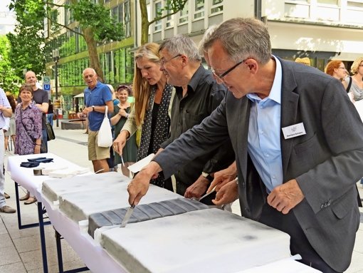 Pfarrer Eberhard Schwarz und Bezirksvorsteherin Veronika Kienzle schneiden die Torte für Bürgermeister Hahn (Mitte) an. Foto: red