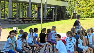 Im Schulhof fläzen die Kinder  auf Bänken in der Sonne: Für die Teilnehmer des Waldheims ist das Riedenberger Gymnasium  ein Ort für Spiel und Spaß. Foto: Rehman