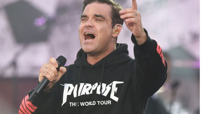 Robbie Williams unterschreibt auf blanken Brüsten