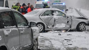 Rettungskräfte stehen am Freitag auf der schneebedeckten B 292 bei Walldorf nach einem Unfall hinter zwei beschädigten Fahrzeugen. Foto: dpa