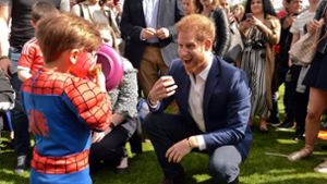 Prinz Harry scherzt mit einem kleinen Jungen, der ein Spiderman-Kostüm auf der Gartenparty trägt. Foto: Sunday Times Pool/AP