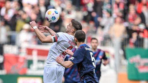 Der Augsburger Ermedin Demirovic (l) behauptet den Ball gegen Heidenheims Benedikt Gimber. Foto: Harry Langer/dpa