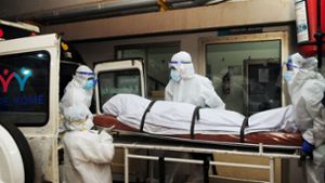 Sanitäter und Ärzte bringen einen der am Nipah-Virus Verstorbenen im indischen  Bundesstaat Kerala unter strengsten Sicherheitsvorkehrungen zur Untersuchung. Foto: AFP