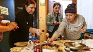 Serap Balles (Im Hintergrund) bereitet mit den Frauen die Füllungen vor. In der Küche (Foto rechts) schöpfen Viktoria Holota (links) und Olena Iastrebynska die Wareniki ab. Foto: Simon Granville