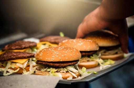 Der Mitarbeiter eines Schnellrestaurants bereitet  Burger zu. Foto: Adobe Stock/Franziska Gabbert