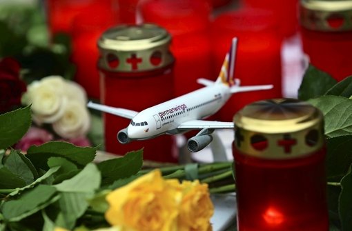 Ein Flugzeugmodell steht in Köln zwischen Blumen und Kerzen vor der Germanwings-Zentrale Foto: dpa