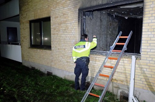 Ein Polizeibeamter leuchtet in die ausgebrannte Wohnung einer geplanten Flüchtlingsunterkunft in Flensburg (Schleswig-Holstein). Foto: dpa