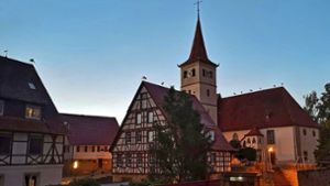 Meister Adebar zur Blauen Stunde in Altdorf: Störche  machen Zwischenstation auf dem Dach der Evangelischen Kirche. Foto: Bernd Kammholz