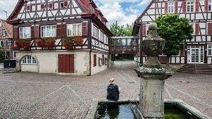 Eine Frau sitzt  an einem Brunnen vor dem Rathaus in Weissach im Tal – nachdem ein geplantes Asylbewerberheim in Flammen aufging, kam der Ort ins Spiegel-Magazin als ein Beispiel für „Dunkeldeutschland“. Foto: dpa