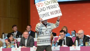 Ein Gegner des Bahnprojekts Stuttgart 21 läuft in Heilbronn beim SPD-Landesparteitag mit einem Plakat über die Bühne. Nach einer kontroversen Diskussion haben die Sozialdemokraten eine Resolution des Landesvorstands zu S21 verabschiedet. Foto: dpa