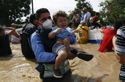 Tropensturm in Honduras: Ein Polizist trägt ein Kind durch eine überflutete Straße Foto: AP/Delmer Martinez