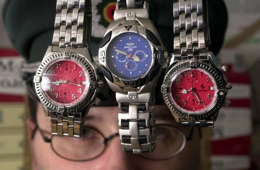 Ein Mitarbeiter des Zollamts  zeigt beschlagnahmte Plagiate der Uhrenmarken Ferrari und Breitling Foto: dpa-Zentralbild