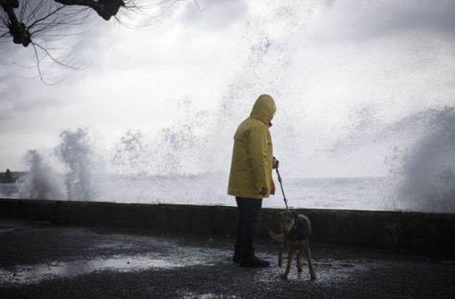 Ein Mann geht bei Rorschach (Schweiz) am Bodensee mit seinem Hund spazieren, während Sturm Burglind die Wellen gegen die Promenade treibt. Foto: dpa