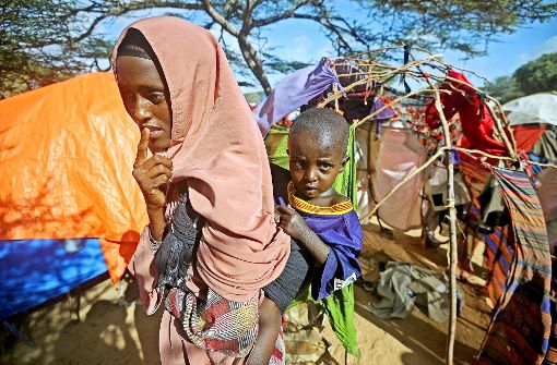 Eine somalische Frau, die in einem Flüchtlingslager untergebracht ist,  trägt ihr kleines Kind auf dem Rücken. Foto:  