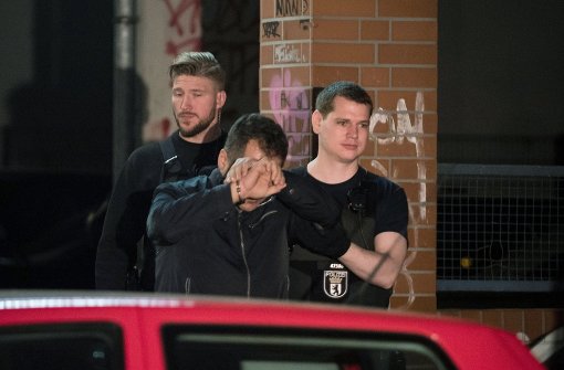 Polizisten führen eine Person in Handschellen aus einem Haus in Berlin im Bezirk Neukölln. Am frühen Morgen gab es hier Hausdurchsuchungen und Festnahmen. Foto: dpa
