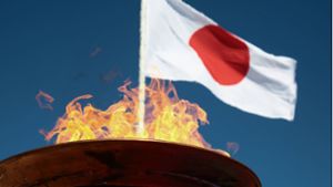 Das olympische Feuer brennt vor der Flagge Japans. Foto: imago//Markos Chouzouris