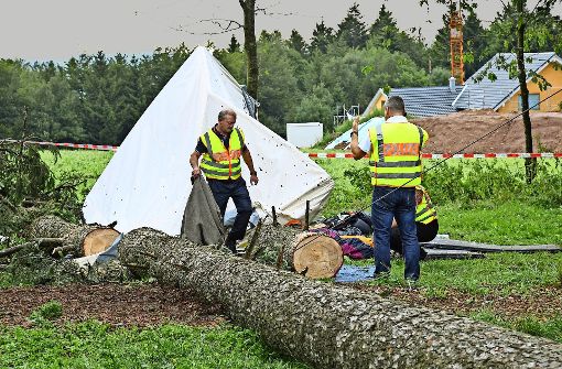 Polizisten untersuchen das beschädigte Zelt, auf das der Baum gestürzt ist.  Ein 15-Jähriger wurde  bei dem Unglück getötet. Foto: dpa