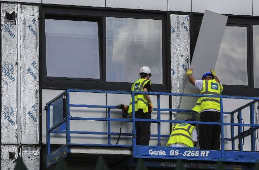 Arbeiter entfernen eine Außenverkleidung an einem Hochhaus, das bei einer Überprüfung als unsicher eingestuft worden war. Foto: AP
