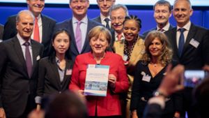 Kanzlerin Angela Merkel hält die Empfehlungen der Wirtschaftsverbände der G-20-Länder in den Händen. An ihrer Seite stehen die Verbandsvertreter. Foto: dpa