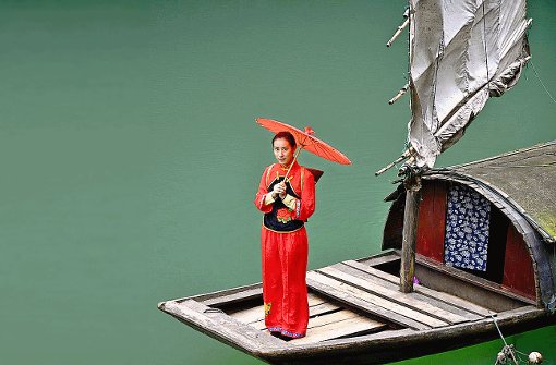 Auf einem Seitenarm des Jangtse steht eine in Rot gekleidete Frau auf einem Boot - einfach nur, damit die Touristen auf dem Schiff ein schönes Fotomotiv haben.  Foto: Rettig