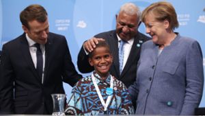 Angela Merkel und der französische Präsident Emmanuel Macron (links)  begrüßen bei der Weltklimakonferenz gemeinsam mit dem Premierminister der Fidschi-Inseln, Frank Bainimarama, einen zwölfjährigen Junge von den Fidschi-Inseln. Foto: dpa