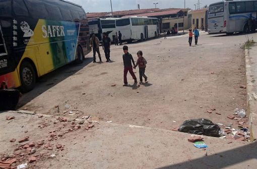 Kinder gehen über den Platz der Busstation Al-Ramusseh westlich von Aleppo (Syrien). Dort hängen rund 2200 Menschen fest, die am Morgen des Vortages in zwei von Regierungskräften belagerten Orten aufgebrochen waren. Foto: Nahel Nur/dpa