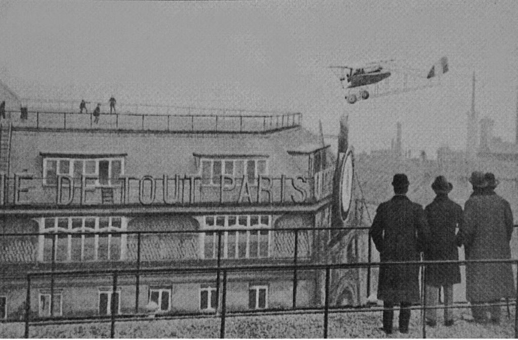 Ein Fotograf hält das waghalsige Luftmanöver von Jules Védrines am 19. Januar 1919 mitten in Paris mit seiner Kamera für die Nachwelt fest.