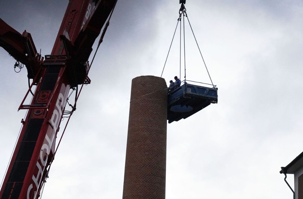Die Arbeiter stehen in luftiger Höhe in einer Art Container-Gondel, die von einem 350 Tonnen schweren Kran gehoben wird.