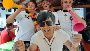Schönauer Fans des Fußball-Bundestrainers halten im Vereinsheim des lokalen Fußballclubs in Schönau ein lebensgroßes Bild des jubelnden Jogi Löws in den Händen. Foto: dpa