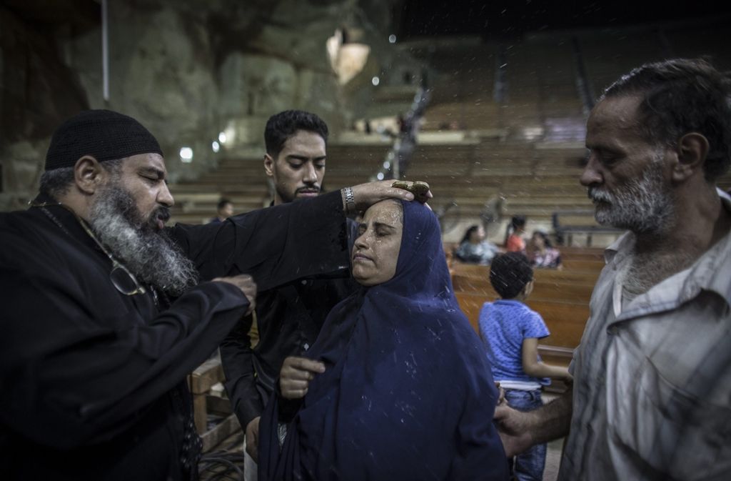Ein Priester besprenkelt eine Frau während eines Exorzismus in „Saint Simon“ mit Weihwasser.