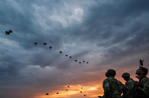 Am Himmel ziehen Transportflugzeuge vorbei,  wie an einer unsichtbaren Schnur ziehen sie Seidenpilze hinter sich her – der Auftrag der Fallschirmjäger: Die feindlichen Kräfte im Rücken anzugreifen. Foto: AFP