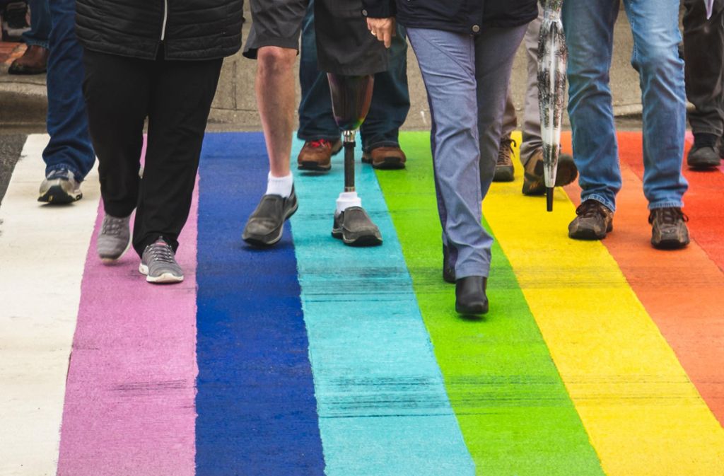 Fußgänger in Utrecht in den Niederlanden laufen über einen Regenbogen-Zebrastreifen.
