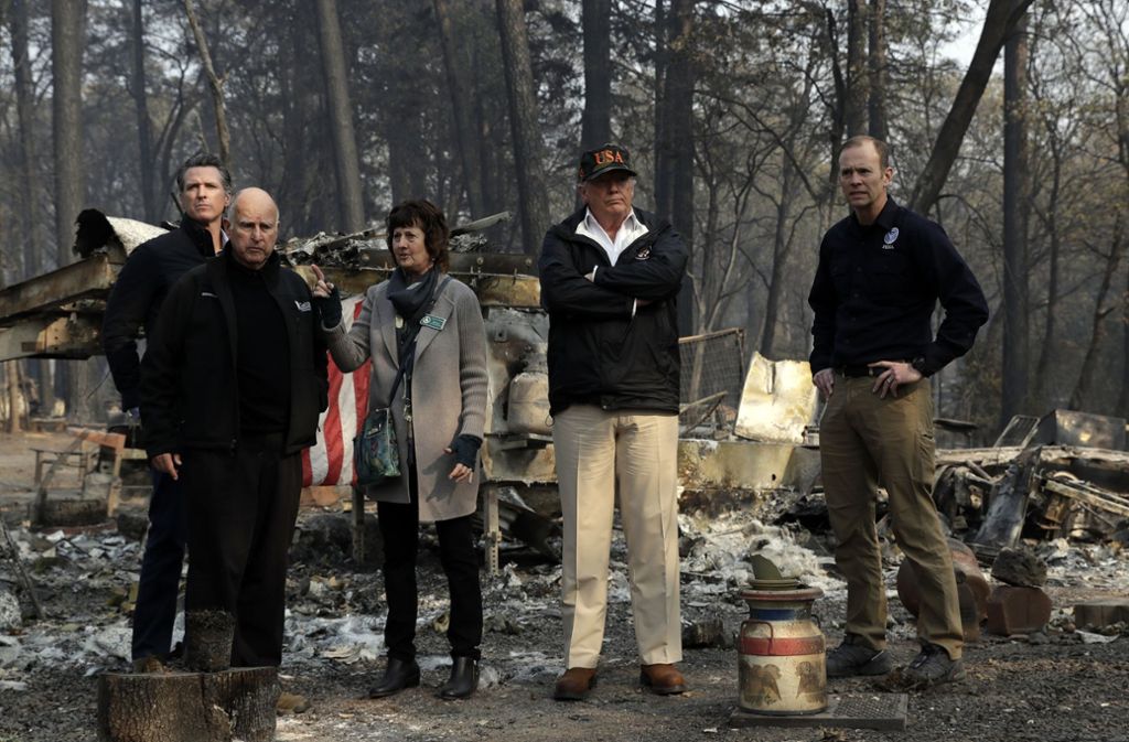 Donald Trump (mit USA-Mütze) inmitten der Zerstörung durch die Waldbrände. Sein Ratschlag, wie die solche Katastrophe verhindert werden können, sorgt allerdings für Kopfschütteln. Foto: AP