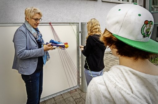 Die Landschaftsarchitektin Regina Traub hilft den Jugendlichen, die Wand mit Wäsche­leinen zu verzieren. Foto: factum/Bach
