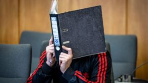 Der Angeklagte verbirgt im Essener Landgericht sein Gesicht hinter einem Aktenordner. Foto: Christoph Reichwein/dpa