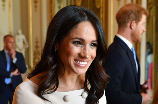 Lächeln, Hände schütteln, Smalltalken: Herzogin Meghan bei einem Empfang im Buckingham Palace. Im Hintergrund: Ihr Mann, Prinz Harry. Foto: dpa