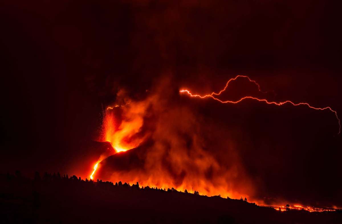 Ein vulkanischer Blitz über dem Vulkan Cumbre Vieja ist trotz des dichten, dunklen Rauchs, der aus dem Krater aufsteigt, von weitem sichtbar.